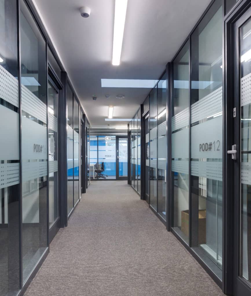 Glass office partitioning along both sides of a corridor