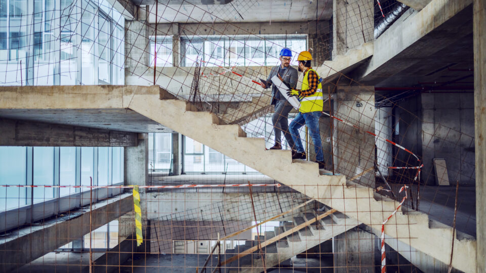 Construction worker and main architect climbing stairs at construction site